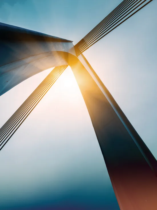 A bridge’s support cables with the sun shining through them.