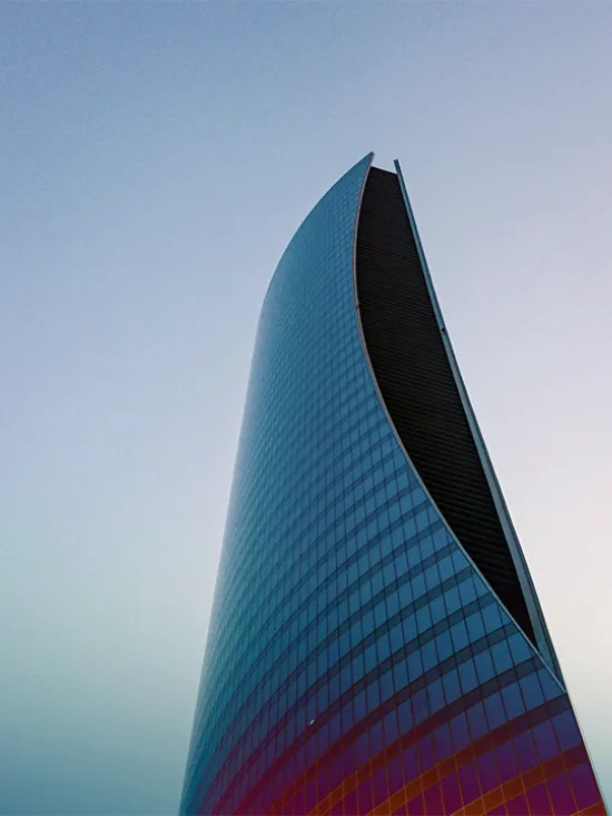 A tall, curved skyscraper with a blue sky in the background.