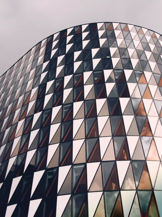 Modern building with a curved facade made up of windows in various shades of blue, gray, and orange.