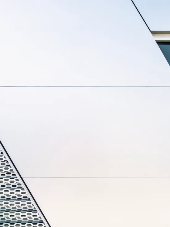 A modern building with a holey metal facade and a white panel.
