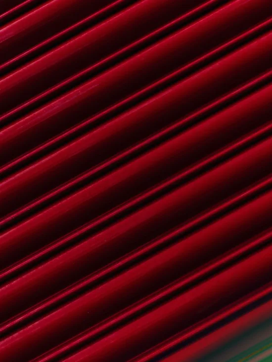 Red, glossy, and parallel lines with a slight reflection of green and blue lights at the bottom.