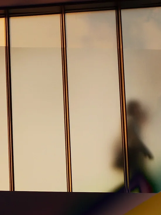 A person going past a window with colorful reflections.