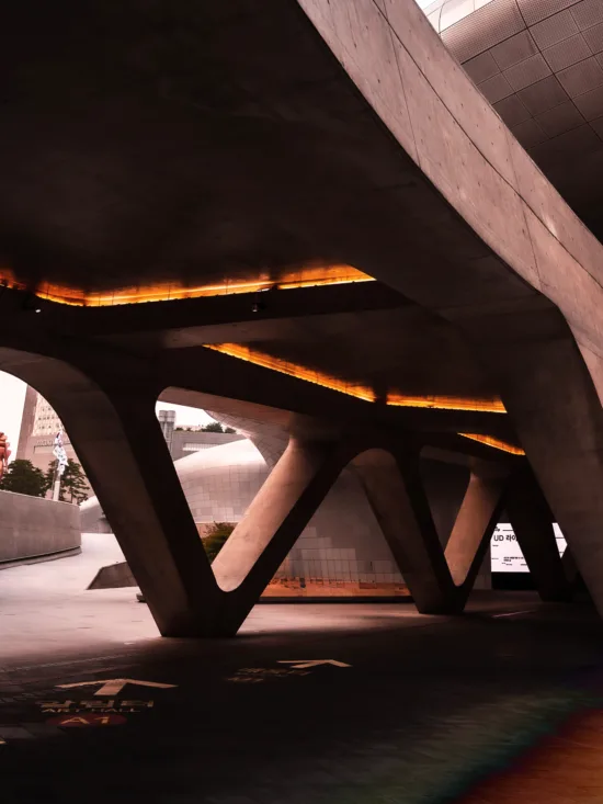 A concrete bridge structure with orange lights shining through the gaps.