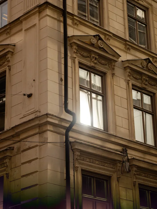 A corner of a building with ornate architectural details and a drainpipe.