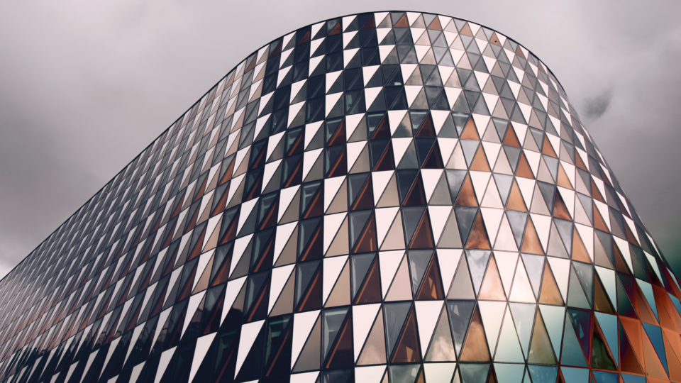 Modern building with a curved facade made up of windows in various shades of blue, gray, and orange.