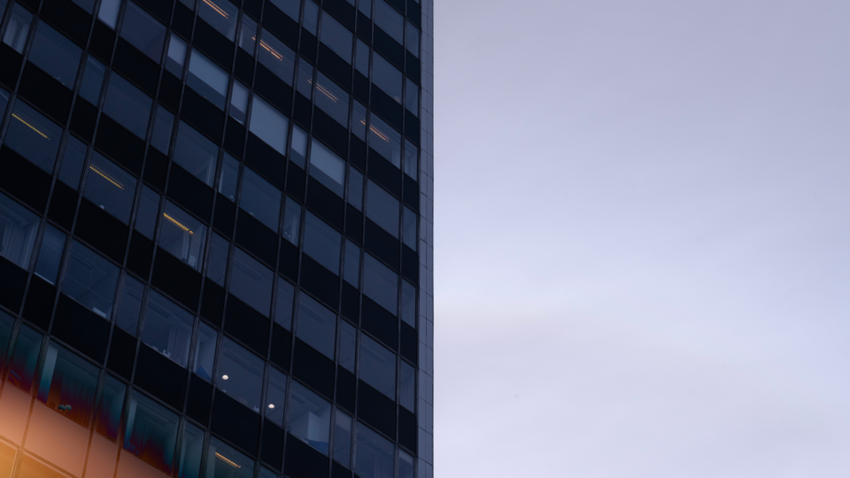 A modern building with reflective glass windows against a clear sky during dusk.