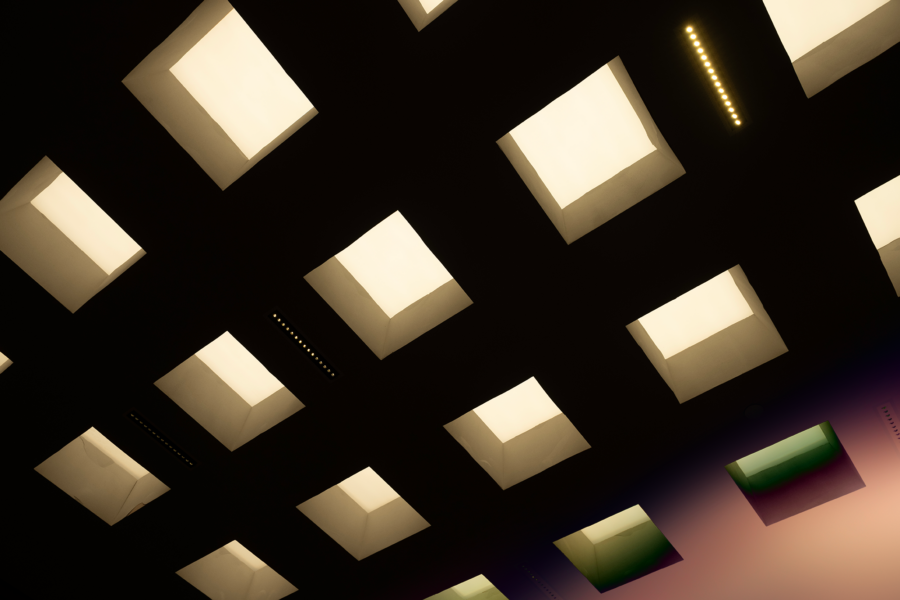 A modern ceiling with a pattern of square and rectangular lights emitting a soft glow.