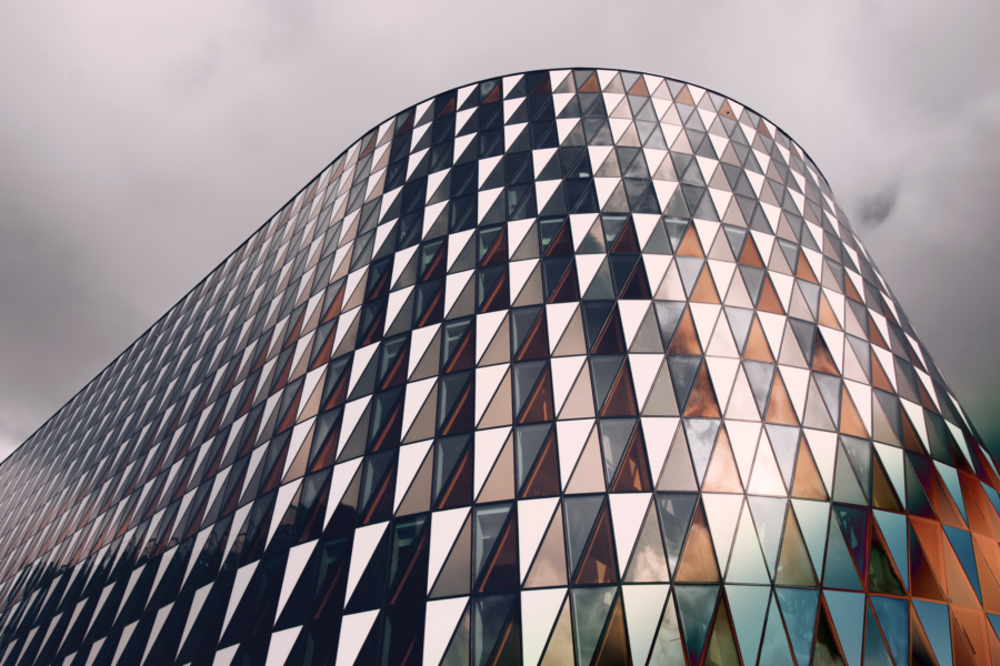 Modern building with a curved facade made up of windows in various shades of blue, gray, and orange.