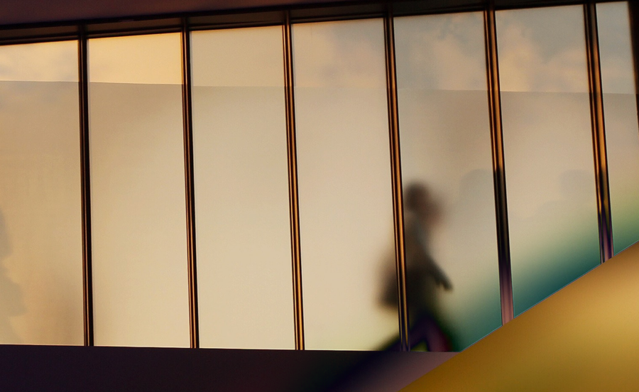 A person going past a window with colorful reflections.
