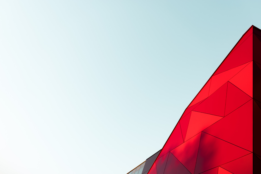 A red and abstract geometric building against a blue sky.