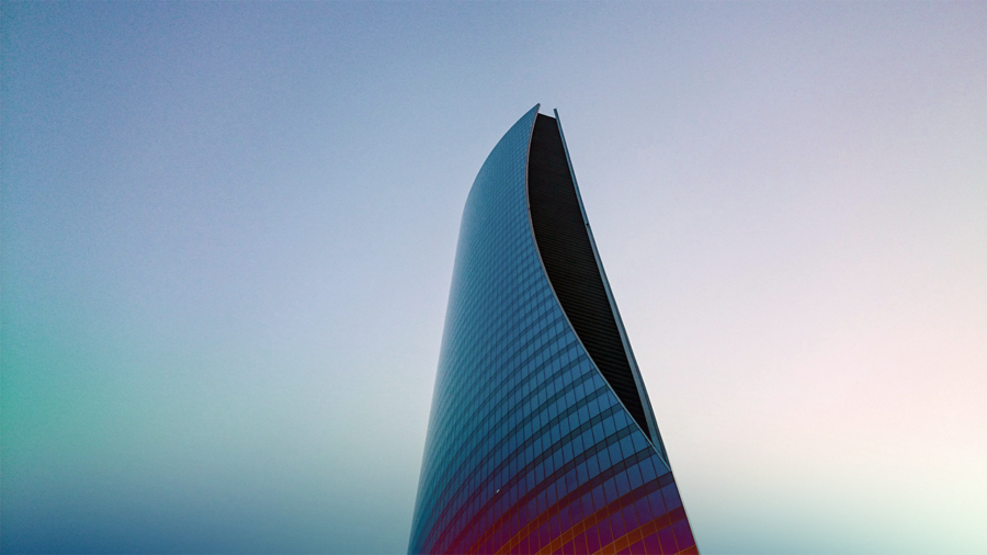 A tall, curved skyscraper with a blue sky in the background.