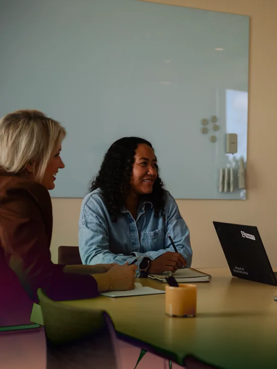 A modern office setting with a group of people seated around a wooden conference table.