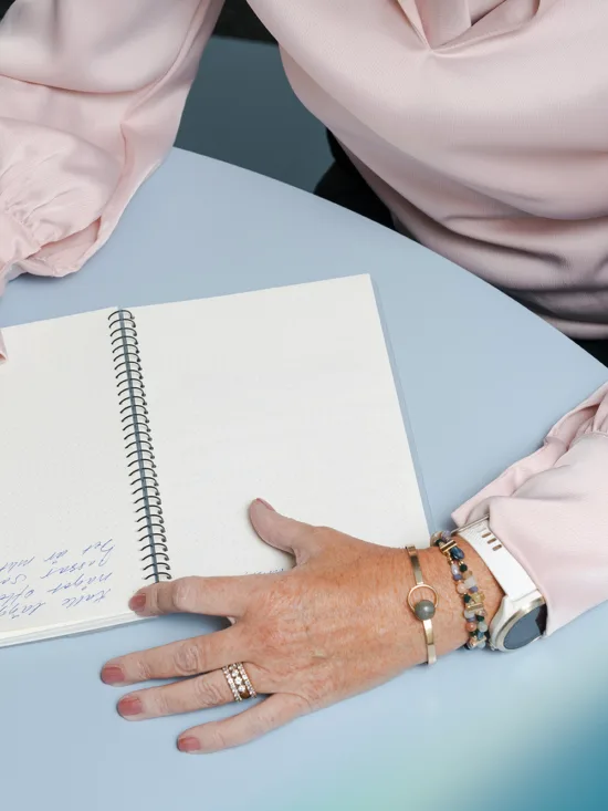 A person’s hands writing in a notebook with a pen.