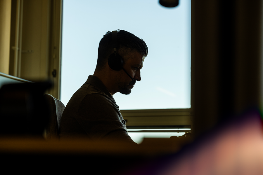 A man sitting by a window attending an online meeting.