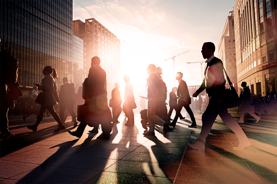 Silhouetted figures walking on a bustling city street at sunset, with tall modern buildings and a vibrant sunset.